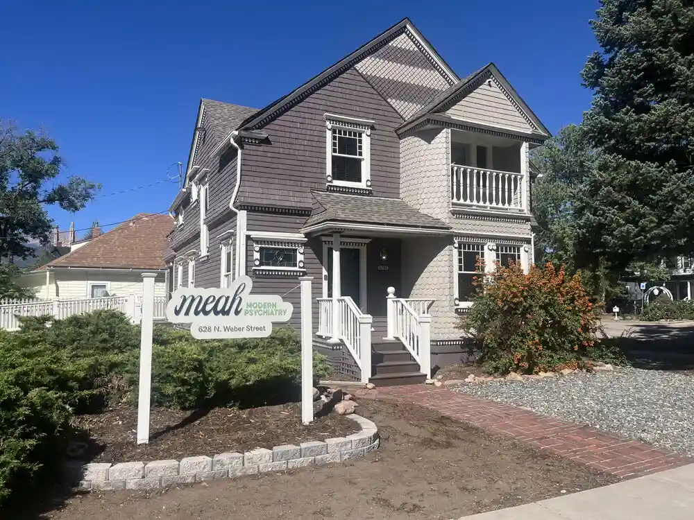 The outside of the Meah Modern Psychiatry office, a two-story gray house with a sign in front reading