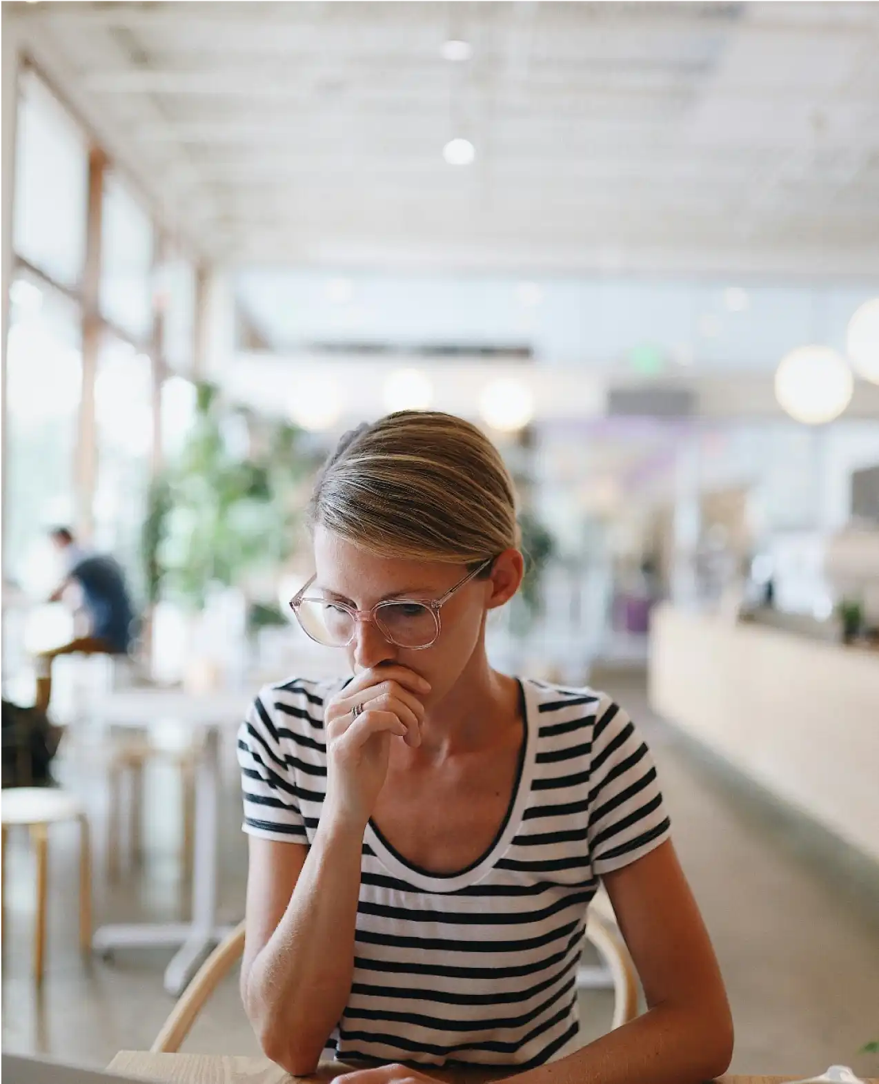 A woman sits with her hand in front of her mouth looking very focused.